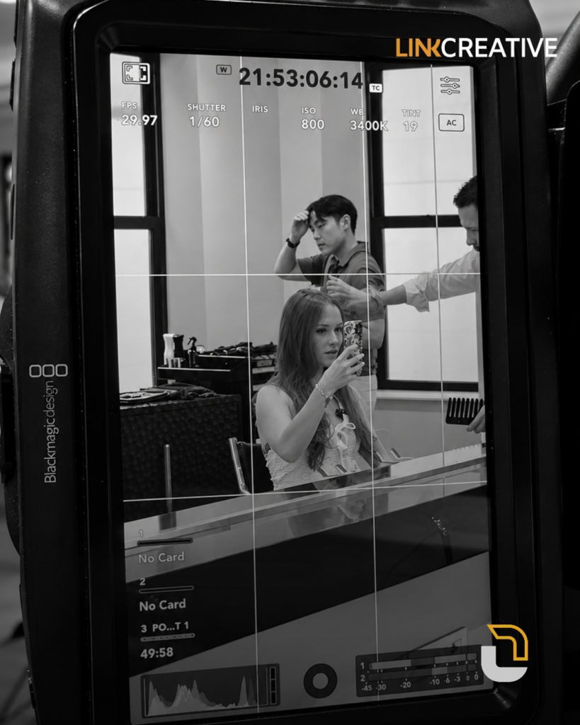 Woman filming a selfie video in a salon chair, seen through a cinema camera monitor during a Link Creative content shoot